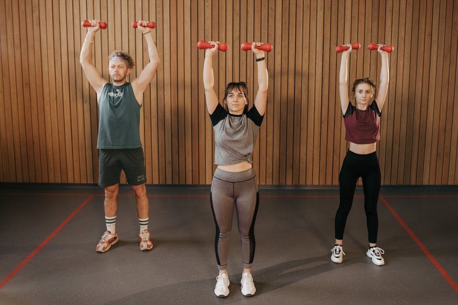 Three adults exercising with dumbbells in a gym setting, promoting fitness and healthy lifestyle.